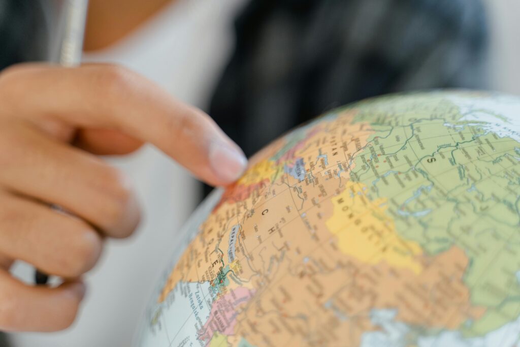 A close-up of a hand pointing at a globe, highlighting exploration and travel concepts.